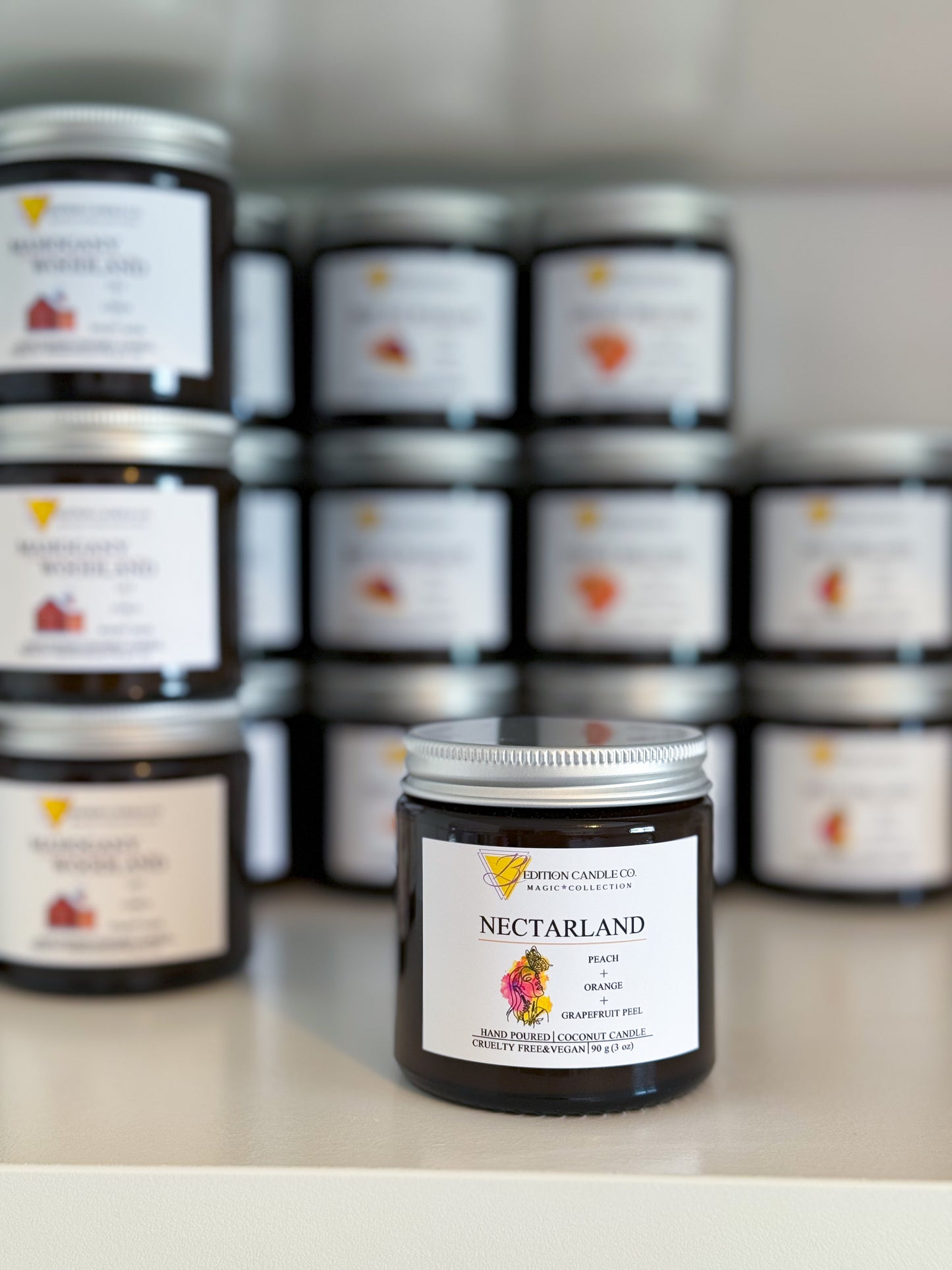 Nectarland peach scented candle displayed in front of a shelf filled with various candle jars.